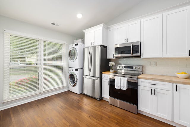 A kitchen furnished with a washer, dryer, fridge, oven and microwave